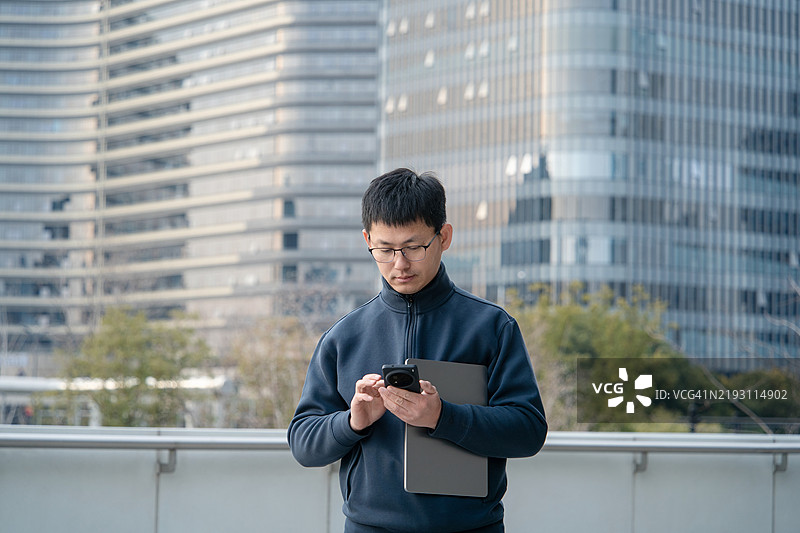 亚洲商人在办公室外拿着智能手机图片素材