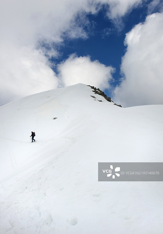 低角度视图的男子在雪山上滑雪，背景是天空图片素材