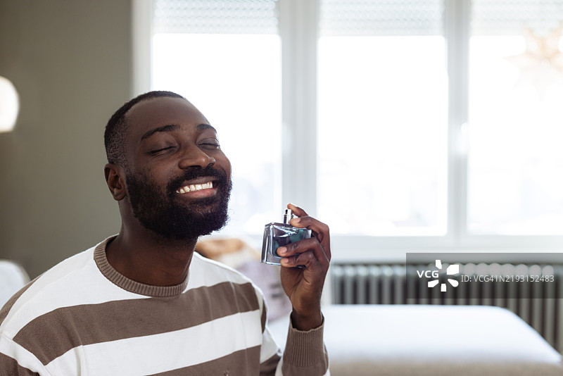 男人在舒适的室内环境中微笑着喷香水图片素材