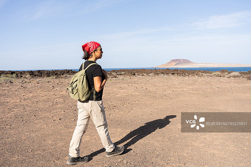 女性徒步旅行者在西班牙加那利群岛兰萨罗特的火山地形中阳光明媚的日子里行走图片素材