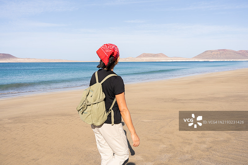 女性在沙滩法马拉海岸徒步旅行，欣赏兰萨罗特火山风光图片素材