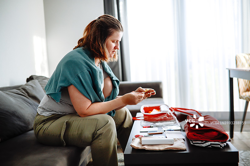 中年女性仔细检查灾难应急包，里面有药品、水和保暖衣物等必需品。图片素材