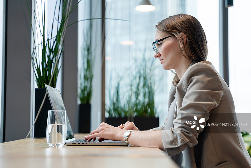 在明亮的办公室空间中工作的职业女性使用笔记本电脑图片素材