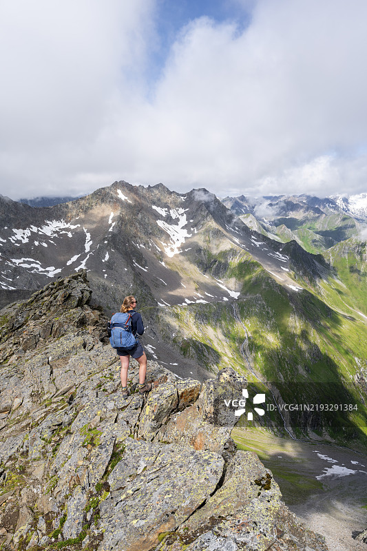 登山者在陡峭的岩石山脊上,站在拉索尔林峰的顶峰,俯瞰维尼迪格山群、拉索尔林山群和高塔恩国家公园的山脉全景,东蒂罗尔,蒂罗尔,奥地利,欧洲图片素材