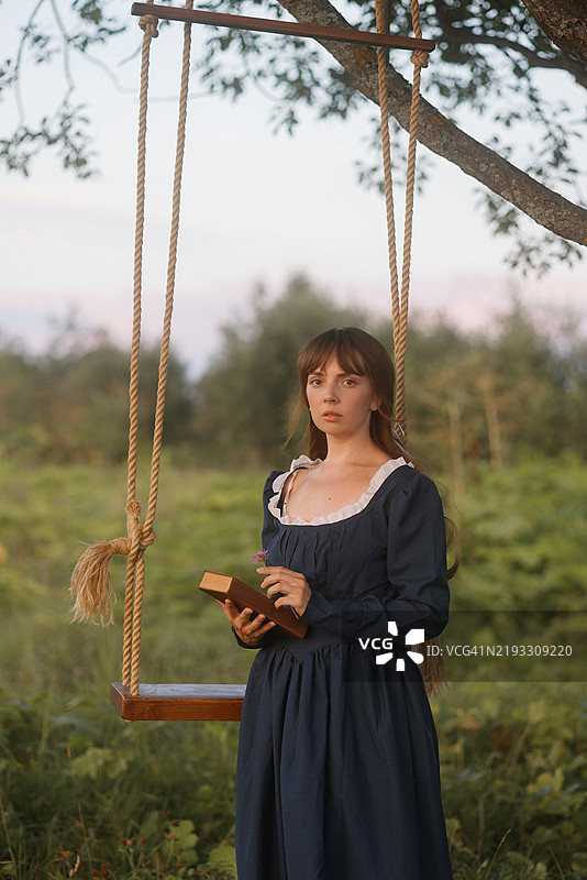 年轻女性在乡村秋千上阅读图片素材