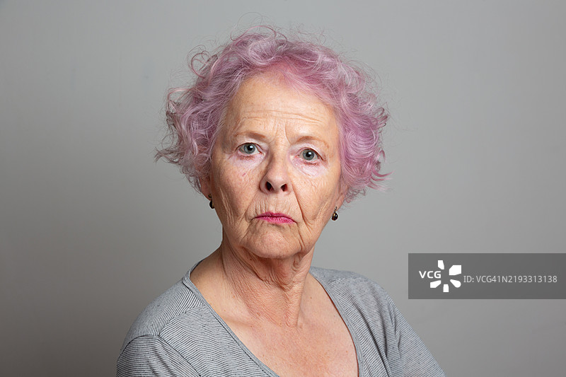 一位银发女性的肖像，粉色头发，表情严肃图片素材