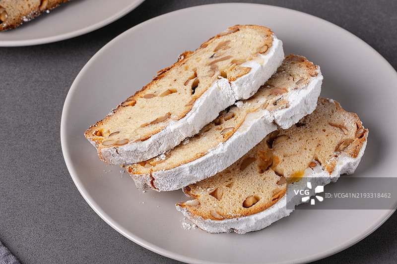 美味的自制圣诞果仁面包摆放在盘子上，撒上糖粉和切碎的坚果，营造出节日气氛。图片素材