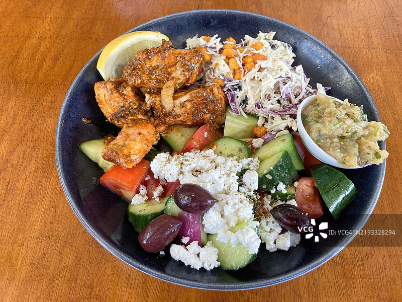 调味腌制鸡肉的碗；希腊沙拉；剁碎的哈卢米奶酪、卷心菜、脆玉米、黑加仑、新鲜香草、大蒜蛋黄酱的凉拌菜；以及烟熏茄子酱图片素材