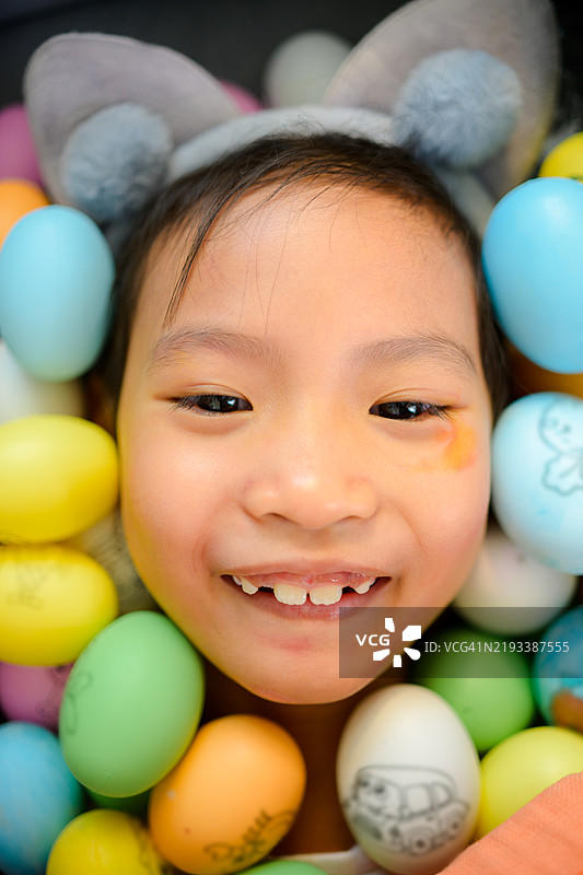 快乐的小女孩正在为复活节涂彩蛋。图片素材