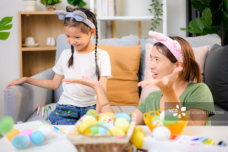 快乐的女孩和年轻母亲一起为复活节涂彩蛋。图片素材