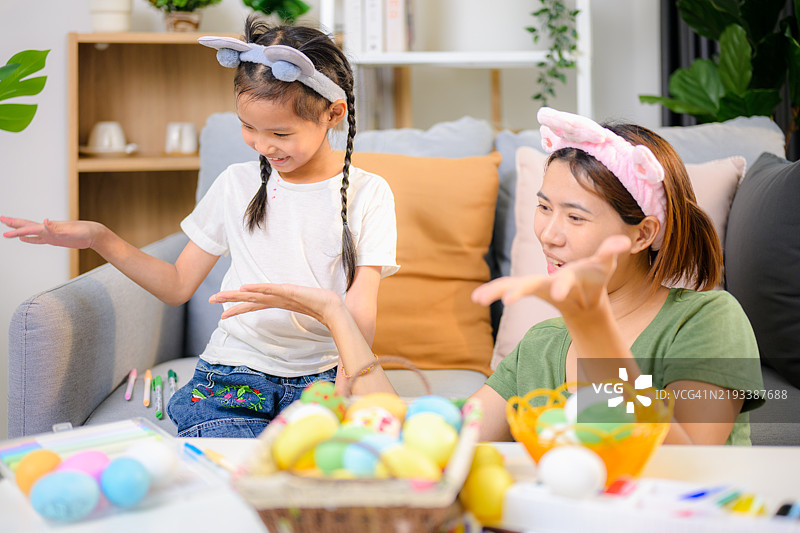 快乐的女孩和年轻母亲一起为复活节涂彩蛋。图片素材