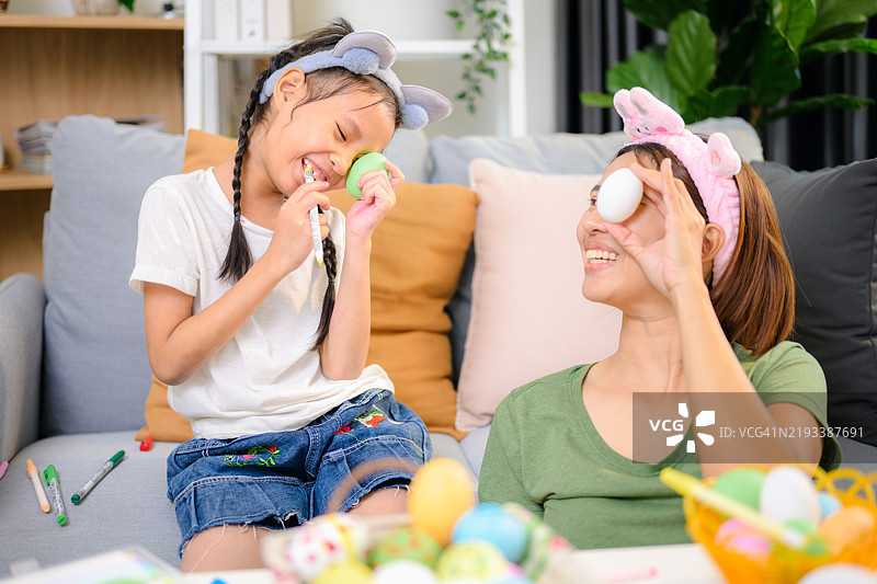 快乐的女孩和年轻母亲一起为复活节涂彩蛋。图片素材