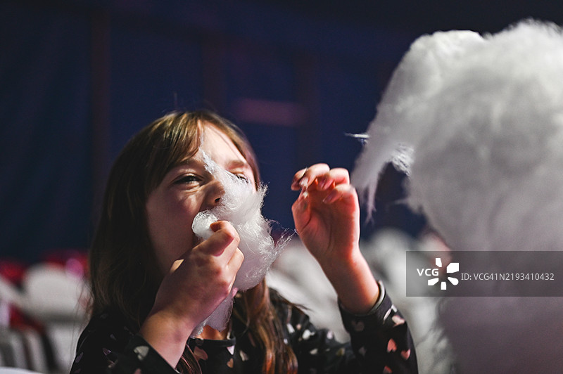 女孩近距离吃着甜棉花糖。图片素材