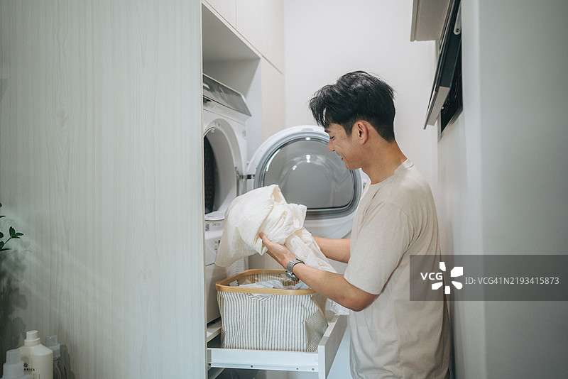亚洲男子在家里洗衣服。泰国曼谷的日常生活活动。图片素材
