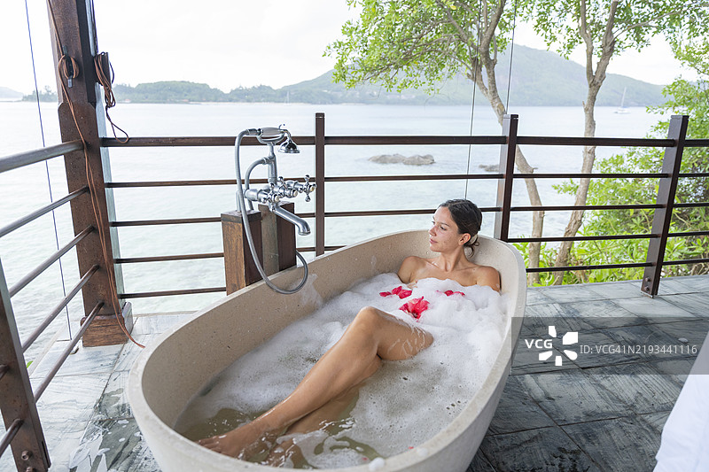 年轻女性在户外浴缸中放松图片素材