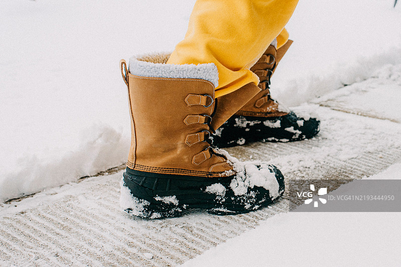 特写镜头：雪地靴在被雪覆盖的人行道上图片素材