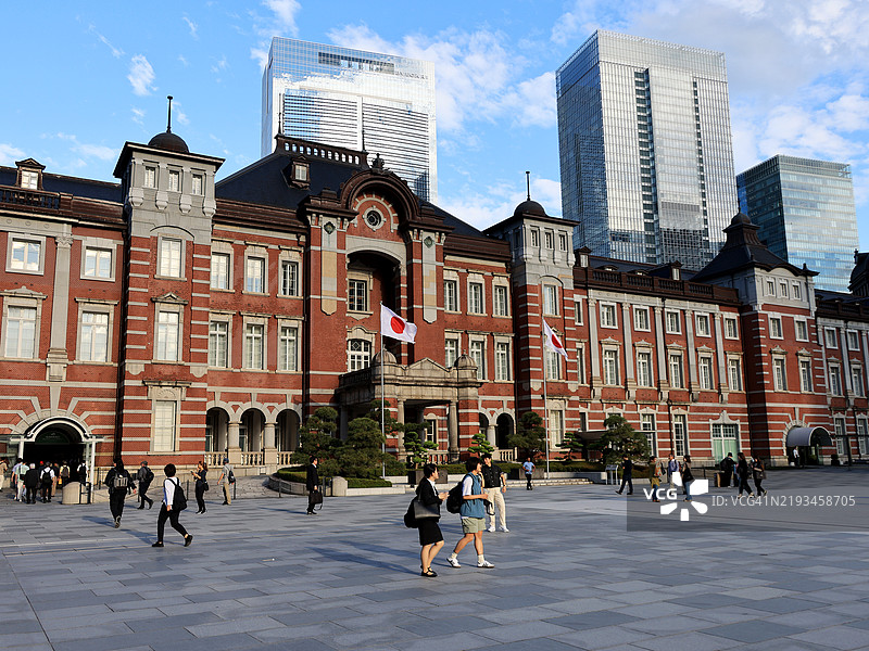 人们在日本东京的东京火车站前走，背景是高楼大厦。图片素材