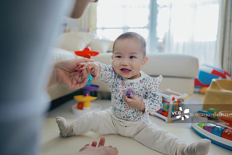 一个亚洲小女孩在客厅里和她的妈妈一起玩玩具图片素材