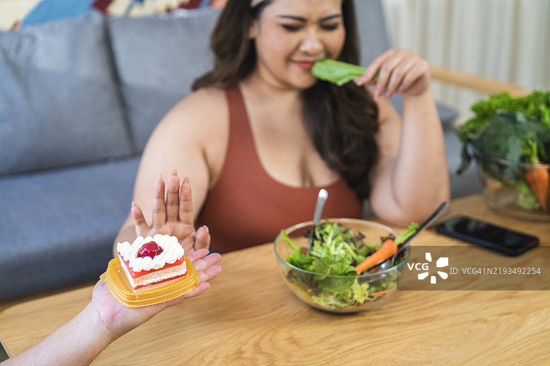 女性拒绝蛋糕，选择沙拉，体现健康饮食理念图片素材
