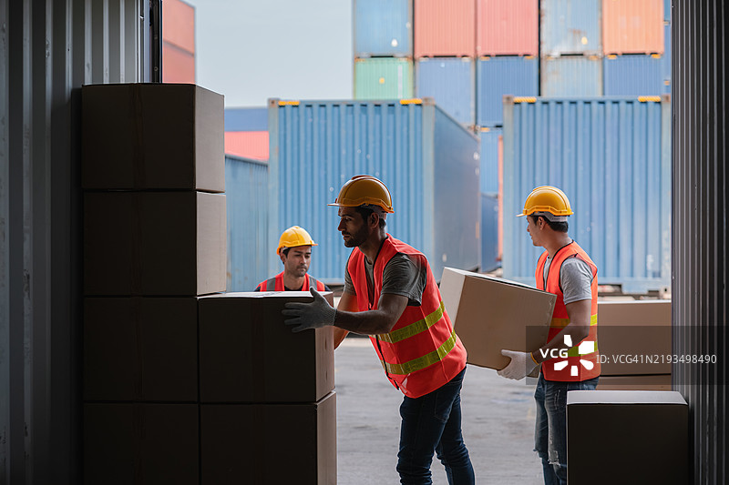 工人们正在从集装箱中卸货箱。图片素材