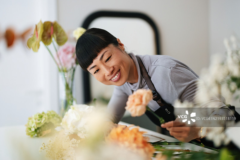 花店花艺师在现代花店中整理五彩缤纷的花朵图片素材