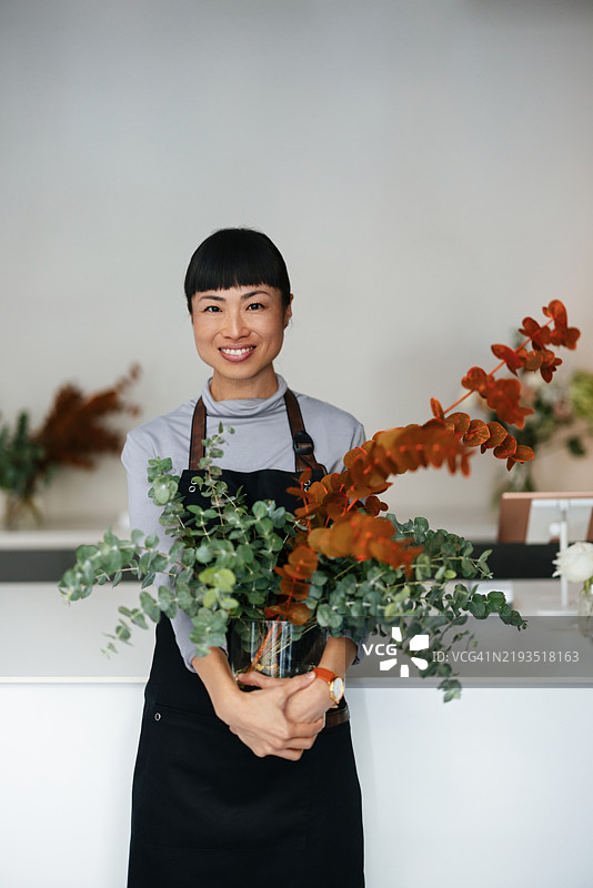 花店里的花艺师手持五彩缤纷的花卉组合图片素材