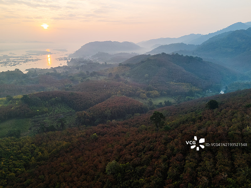 壮观的日出航拍视角，森林覆盖的山丘、蜿蜒的河流，以及水面上的金色倒影。图片素材
