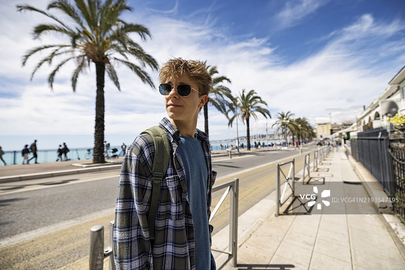 在法国阿尔卑斯-海岸的尼斯，人行道上走着一个帅气的少年。图片素材
