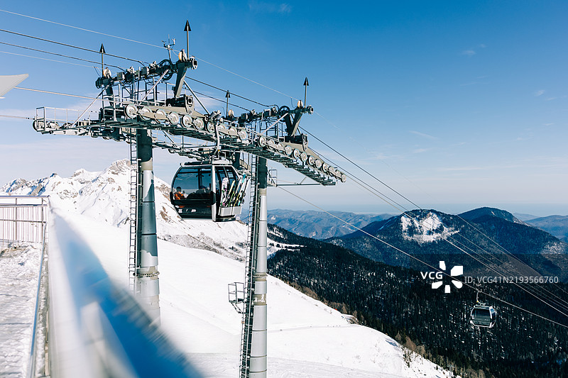 缆车在阳光明媚的冬日将滑雪者运送到雪山坡上图片素材