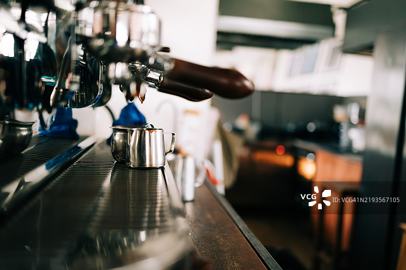 咖啡馆中浓缩咖啡机将咖啡倒入金属壶中图片素材