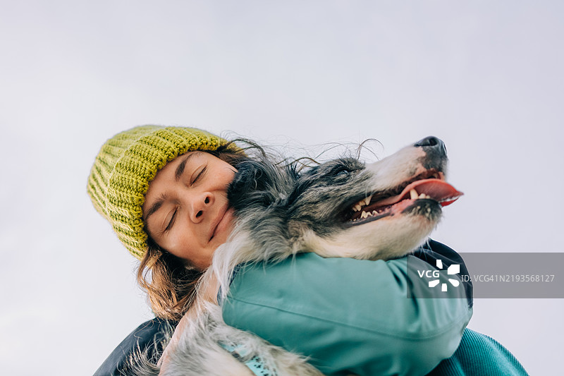 穿着针织帽的女人抱着她的边境牧羊犬图片素材