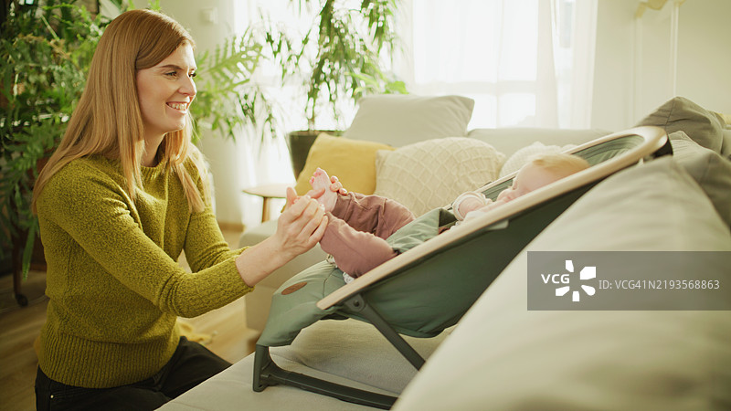 红发母亲在家中为宝宝按摩脚丫。图片素材