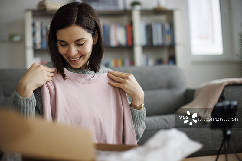 兴奋的年轻女性正在为她的社交媒体平台制作开箱和评测视频内容图片素材