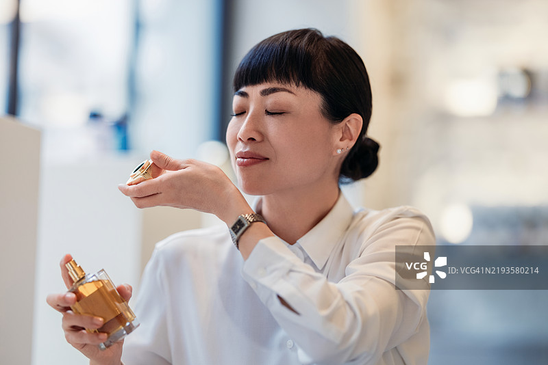 优雅环境中欣赏香水香气的女性图片素材