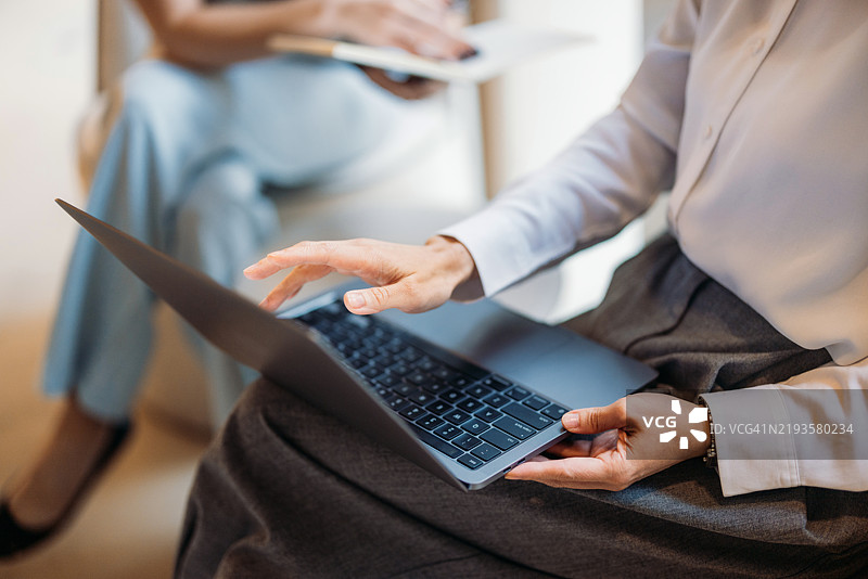 商务女性在办公室环境中参加专业会议时使用笔记本电脑工作图片素材