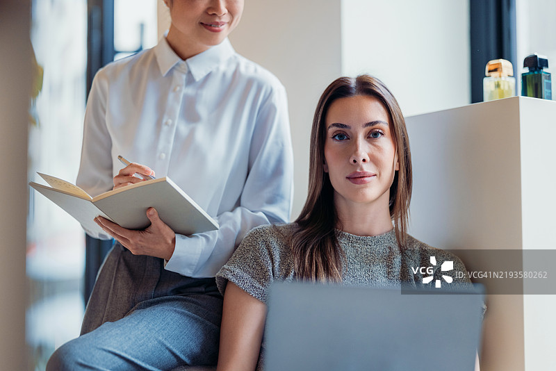 两位女性在现代办公室环境中合作进行专业项目图片素材