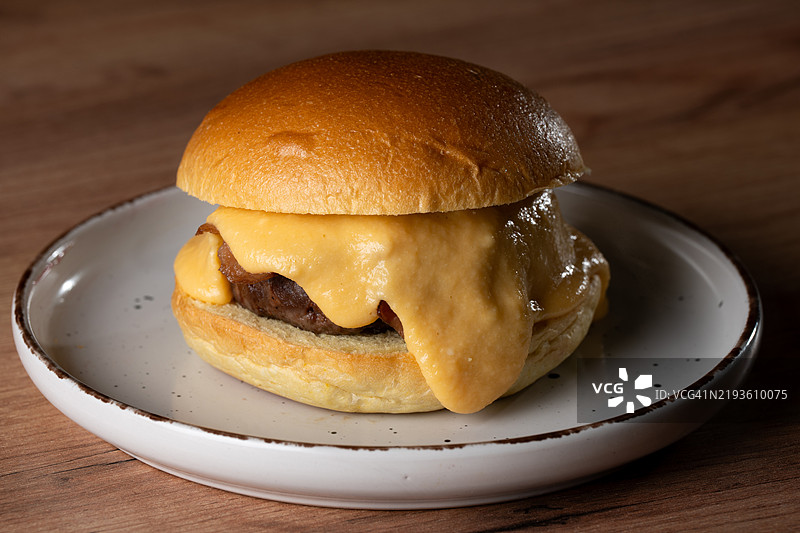 美味的芝士汉堡在餐厅的盘子上融化。图片素材