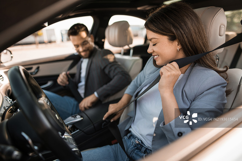 快乐的女商人与同事在车里系安全带图片素材