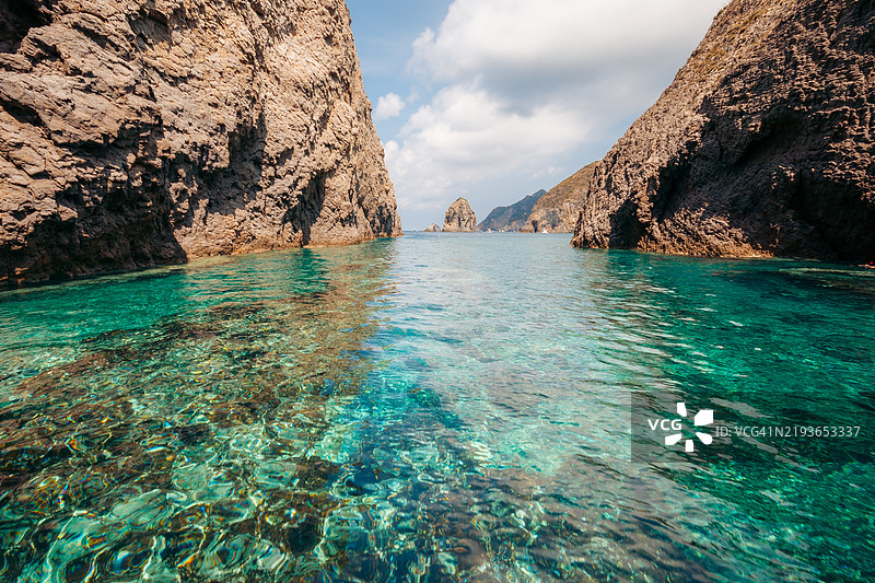 清澈的水环绕着岩石悬崖。意大利，拉齐奥，帕尔马罗拉岛图片素材