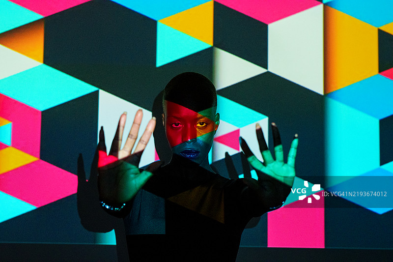年轻艺术家在屏幕上表演，背景是五彩斑斓的几何投影图片素材