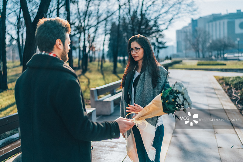 男士手捧花束在约会中向女友道歉图片素材