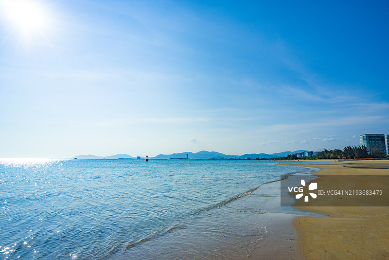 在海边小镇旁，深蓝色的海水冲刷着金色的沙滩图片素材