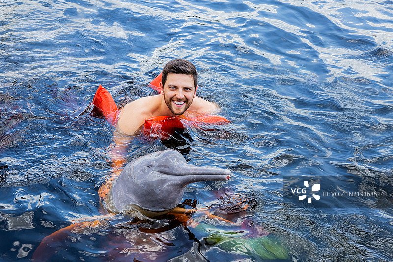 一名中年男子在亚马逊旅行中与海豚一起游泳的肖像图片素材