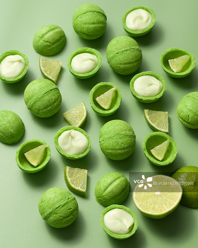核桃形饼干或油酥饼，夹有青柠奶油馅，背景为绿色。带有柑橘、香茅的糕点。坚果。甜点概念。甜食。糖果。烘焙。小吃。面粉制品。特写。图片素材