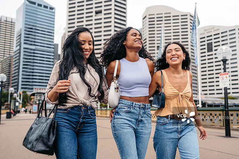 三位年轻女性朋友在澳大利亚悉尼的达令港散步图片素材