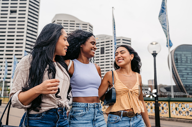 三位年轻女性朋友在澳大利亚悉尼的达令港散步图片素材