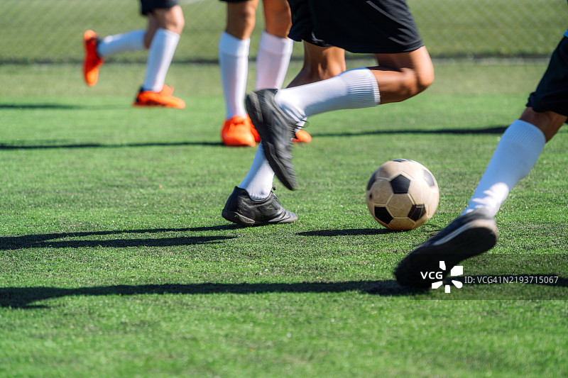 专注的孩子们在球场上一起踢足球，充满活力。图片素材