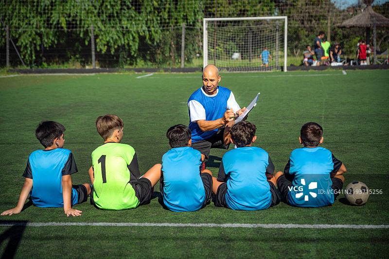 教练在绿茵场上指导年轻足球运动员训练图片素材