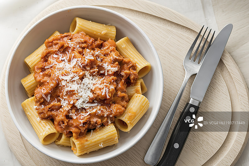 从上方俯视一块浅色木板，上面放着一部分意大利通心粉配博洛尼亚酱。图片素材