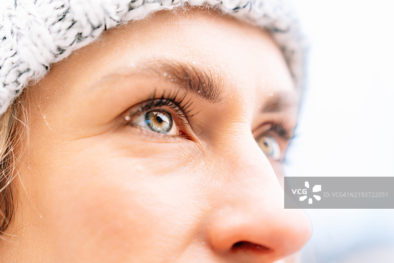 在雪白的冬季景观中，女人深思熟虑地凝视着远方。图片素材